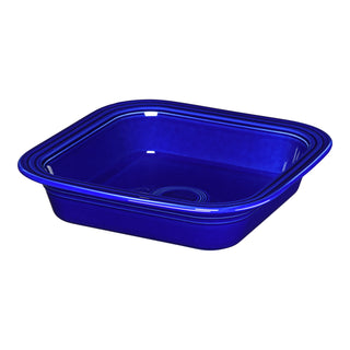 The Retired Fiesta Square 9x9 Inch Baker, a 2-quart deep blue ceramic dish with rounded edges and a glossy finish by Fiesta, made in the USA, is shown angled against a white background.