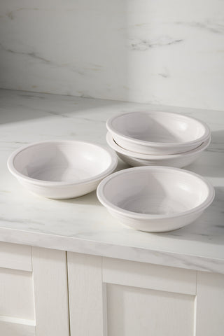 Four Fiesta White Set of 4 Classic Rim 8 3/8-Inch 34OZ Pasta Bowls are stacked on a white marble countertop, with matching backsplash and a white paneled cabinet below.