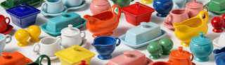 A colorful assortment of ceramic kitchenware, including butter dishes, gravy boats, sugar bowls, salt and pepper shakers, and creamers, arranged on a white background.