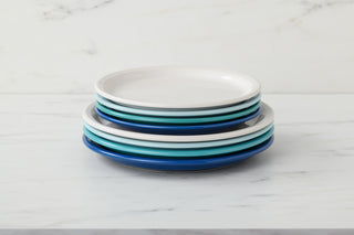 A stack of eight Fiesta Bistro Coupe 9 Inch Luncheon Plates in blue and white rests on a white marble surface with a light marble background. Made in the USA.