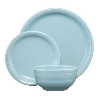 A set of light blue ceramic dinnerware, including a large plate, a smaller plate, and a bowl, all with subtle circular ridge patterns.