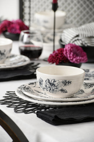 Create an elegant table setting with the Fiesta Botanical Floral Black Classic Bistro 3-Piece Dinnerware Set, Service For 1. Featuring a matching floral-patterned plate and bowl, this set is beautifully complemented by a black placemat and napkin, delicate pink flowers, and a glass of red wine on a crisp white tablecloth—making it the perfect bistro place setting for any occasion.
