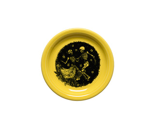 The Fiesta Retired Skeleton Duet Sunflower Bistro Coupe Appetizer Plate (6 1/4") features two skeletons dancing in a dark center circle, with floral accents. Made of yellow ceramic in the USA.