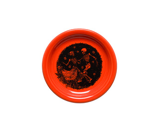 The Fiesta Retired Skeleton Duet Poppy Bistro Coupe 6 1/4 Inch Appetizer Plate is a bright orange vitrified china plate with black dancing skeletons and floral designs. This whimsical, Halloween-themed plate is dishwasher safe and made in the USA.