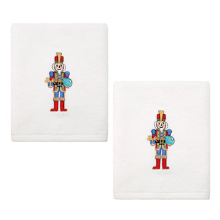 Bring festive cheer to your décor with the Fiesta Nutcracker The Giver Embroidered Hand Towel Set of 2—white cotton towels, each featuring a toy soldier in a red uniform, blue drum, and red boots, standing at attention.