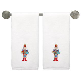 The Fiesta Nutcracker The Giver Embroidered Hand Towel Set of 2 features white cotton towels adorned with festive toy soldiers—perfect holiday decor for your bathroom.