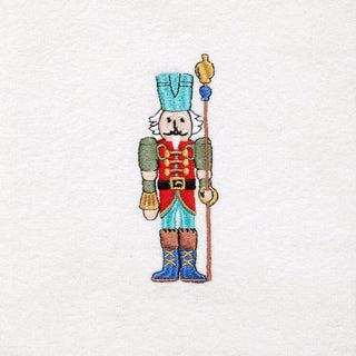 The Fiesta Nutcracker The Guardian Embroidered Hand Towel Set of 2 features a soldier in a blue hat, red and green uniform, blue boots, and golden staff on white fabric—festive holiday towels for your home.