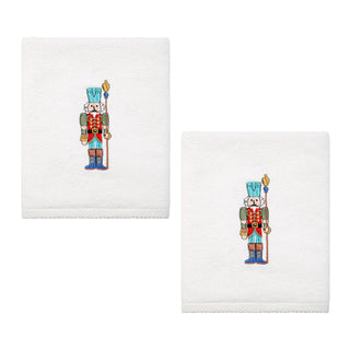 The Fiesta Nutcracker The Guardian Embroidered Hand Towel Set of 2 features white towels with embroidered nutcracker soldiers in blue hats and red jackets, folded neatly and displayed side by side on a plain background.