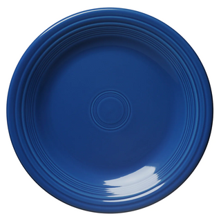 A round, dark blue ceramic plate with concentric circular ridges near the rim, shown from a top-down view against a white background. There is a glossy reflection on the lower right side.