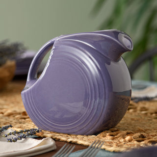 Lavender Large Disk Pitcher on a woven table runner.