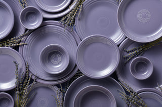 Stack of lavender ceramic plates and bowls with lavender flowers.