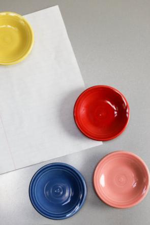 Four Retired Fiesta 3 Inch Magnet Mini Dinner Plates in yellow, red, blue, and pink are displayed on a gray surface next to a sheet of white paper.
