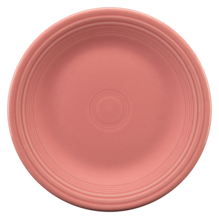 A round, pink ceramic plate with a smooth surface and concentric circular ridges near the edge, viewed from above on a white background.
