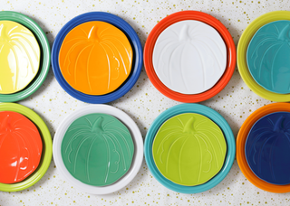 Set of eight Fiesta Retired Pumpkin Shaped Plates (8½"), each in a different color: orange, white, yellow, green, blue, red, teal, and navy. Made in the USA with lead-safe china; shown in two rows on a white speckled background.