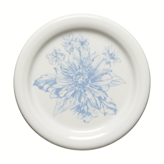 Introducing the Fiesta Botanical Floral Sky 4 3/8 Inch Coaster and Mug Cover—a white ceramic piece from our celebrated botanical floral dinnerware collection. Showcasing a light blue floral design with large petals and leaves at its center, surrounded by delicate smaller flowers, this expertly crafted item is made in the USA and brings elegance and artistry to any table setting.