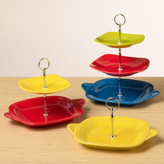 Fiesta’s retired Square Handle Tray w/Hole, featuring brightly colored 13.375" x 10.75" yellow and red plates, is displayed with three-tier hardware on a light wood surface alongside extra yellow and red plates.