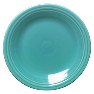 A round, turquoise ceramic plate with a glossy finish, featuring concentric ridge details near the rim. The plate is empty and photographed from above on a white background.