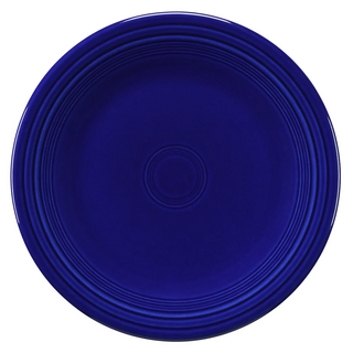A round, deep blue ceramic plate with concentric circular ridges near the rim and center, set against a white background.