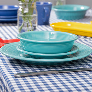 A set of three turquoise dishes—a bowl, salad plate, and dinner plate—from the Fiesta Retired Classic Rim 12-Piece Dinnerware Set (Service for 4) sit on a blue-and-white checkered tablecloth. This lead-safe china is dishwasher safe.