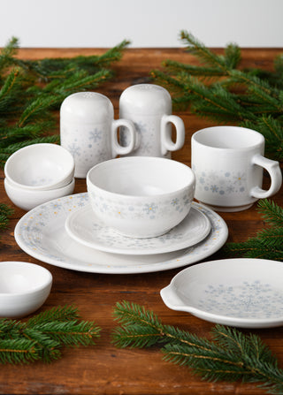 The Fiesta White Snowflake Classic Rim 9 Inch Luncheon Plate, made in the USA, showcases a charming blue snowflake pattern on white ceramic. Perfect for holiday gatherings, this plate brings festive warmth and style to your table setting.