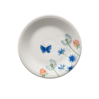 The Fiesta Retired Breezy Floral Classic Rim 7 1/4 Inch Salad Plate is a white ceramic plate made in the USA, featuring blue butterflies and colorful blooms concentrated on one side.