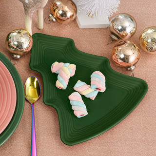 A green, tree-shaped plate with pastel twisted marshmallows sits on a glittery pink surface, surrounded by gold ornaments, a rainbow-colored spoon, and festive decorations.