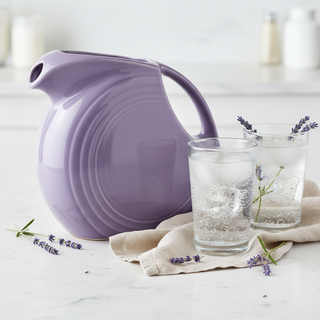 Lavender 67 OZ Large Disk Pitcher on white marble with highball glasses of sparkling water, linen napkin and lavender garnish