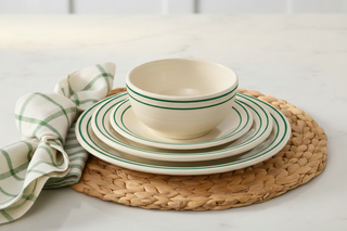 The Fiesta Americana Jade Band Classic Bistro 3-Piece Dinnerware Set, Service For 1, in cream with striking green stripes, is displayed on a woven placemat alongside a folded green-and-white checkered napkin, set upon a white countertop. Proudly made in the USA.