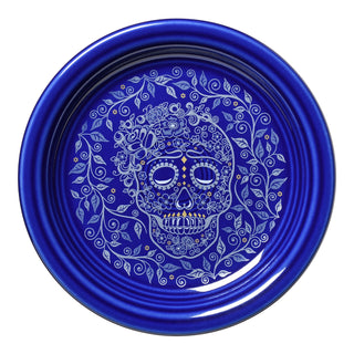 The Fiesta Retired SKULL AND VINE TWILIGHT Bistro Coupe 6 1/4 Inch Appetizer Plate features a blue finish with an intricate white sugar skull, floral and vine design, crafted from lead-safe china and inspired by Día de los Muertos motifs.