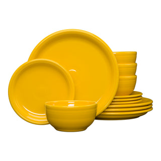 A stack of daffodil-colored Fiesta Bistro Coupe 12-Piece Dinnerware Set, Service for 4, featuring plates and bowls in a modern coupe design, displayed on a white background.