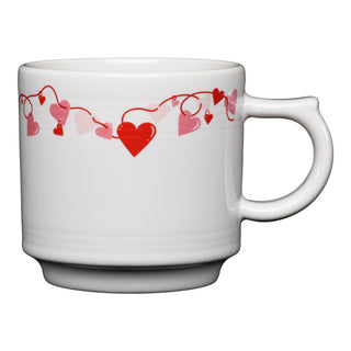 The Fiesta Retired Valentine 16 OZ Stackable Mug features a white vitrified china design with red and pink hearts linked by a wavy line near the rim. Dishwasher safe, with the handle positioned on the right side for easy use.