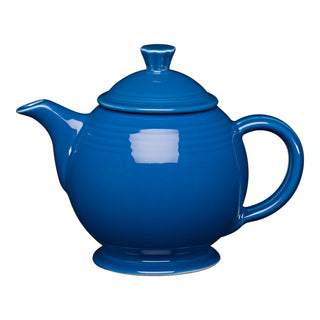 The Retired Fiesta 44 OZ Covered Teapot by Fiesta in lapis features a round shape, curved spout, large handle, and lid. Lead-safe and dishwasher safe, this vibrant teapot stands out against a plain white background.