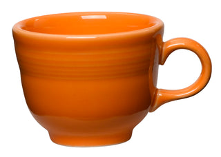 The Fiesta Retired Classic 7 3/4 OZ Tea Cup is an orange ceramic cup with a handle, made in the USA. It features a glossy finish, horizontal ridges near the top, and is displayed against a white background.