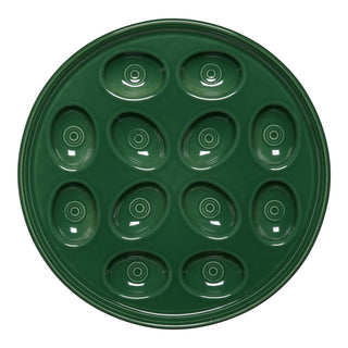 The Fiesta Retired Round Egg Serving Platter in Jade is an 11 1/4-inch, dark green ceramic plate with twelve oval indentations in a circle, each with concentric rings. Made in USA, lead-safe china.