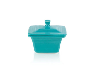 The Fiesta Retired Covered Box (4 5/8" x 3 3/4") in turquoise features a square ceramic design with a matching lid and knob handle—ideal for stylish storage. Made in the USA and shown against a white background.